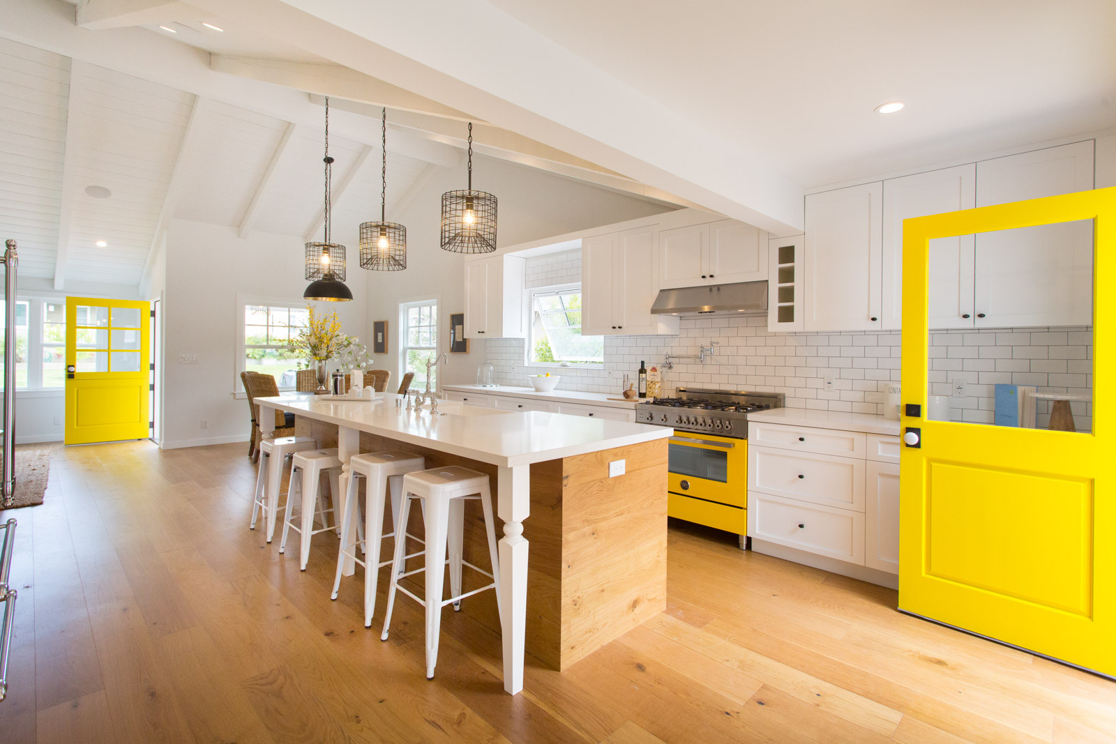 A wood and white kitchen with a yellow stove and yellow doors with colonial style white Milgard windows. 