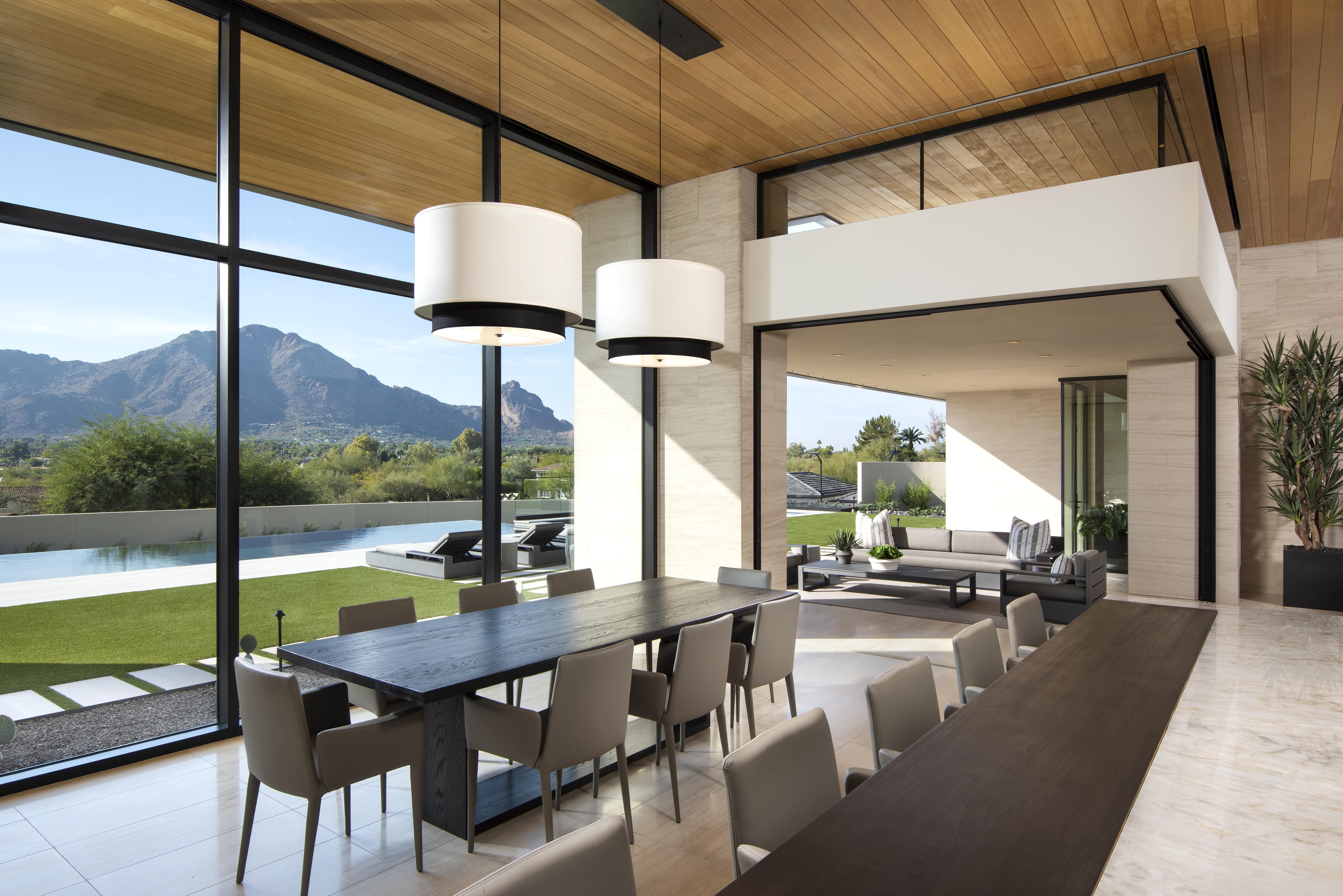 Modern style dining room with floor to ceiling windows viewing backyard.