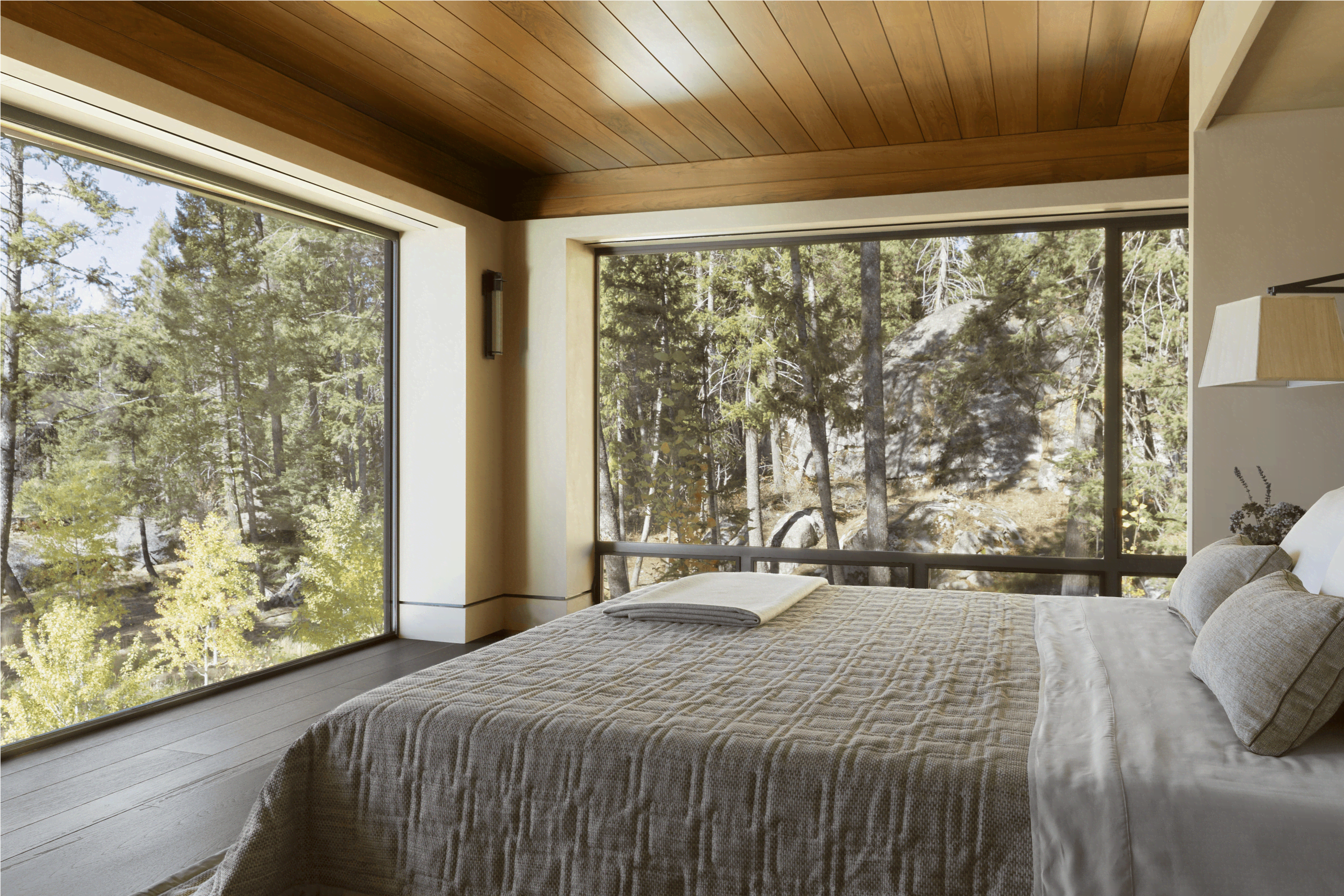 Modern bedroom in a forest house with large panoramic windows.