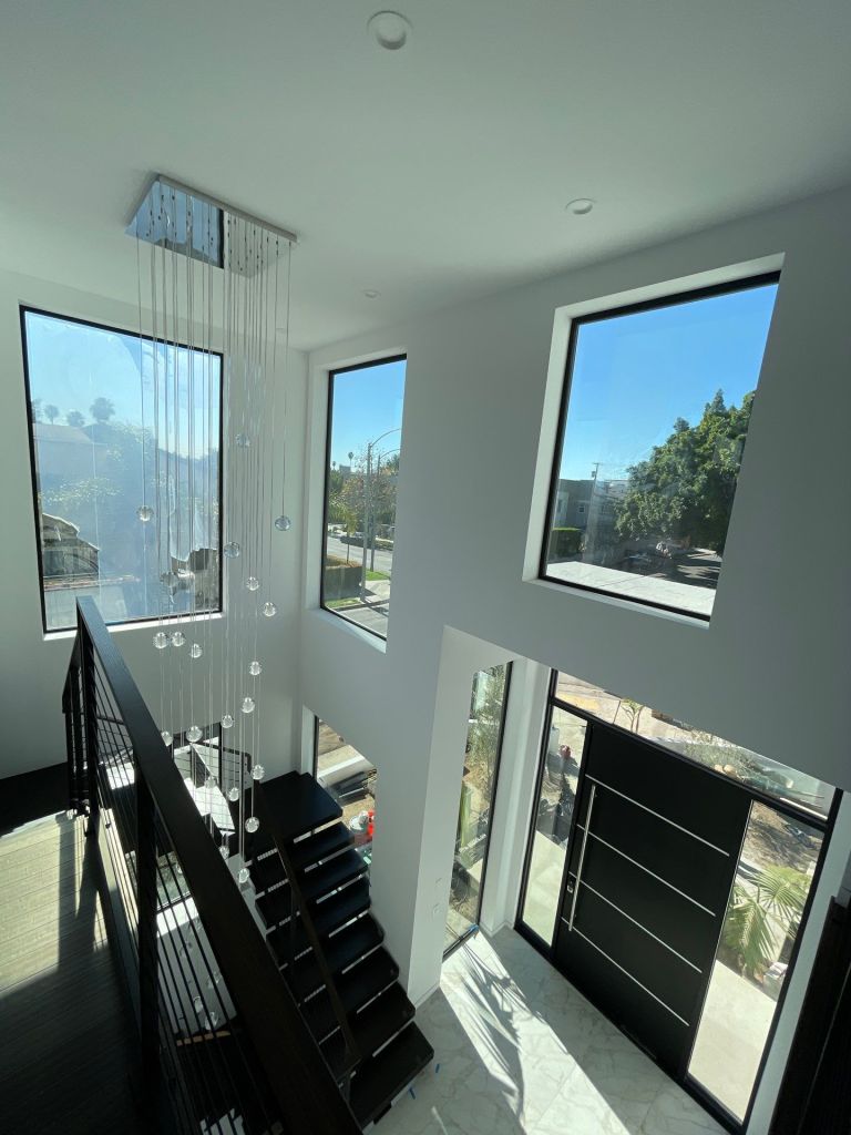 Custom large square windows with black aluminum frame and modern pull handle entry door.