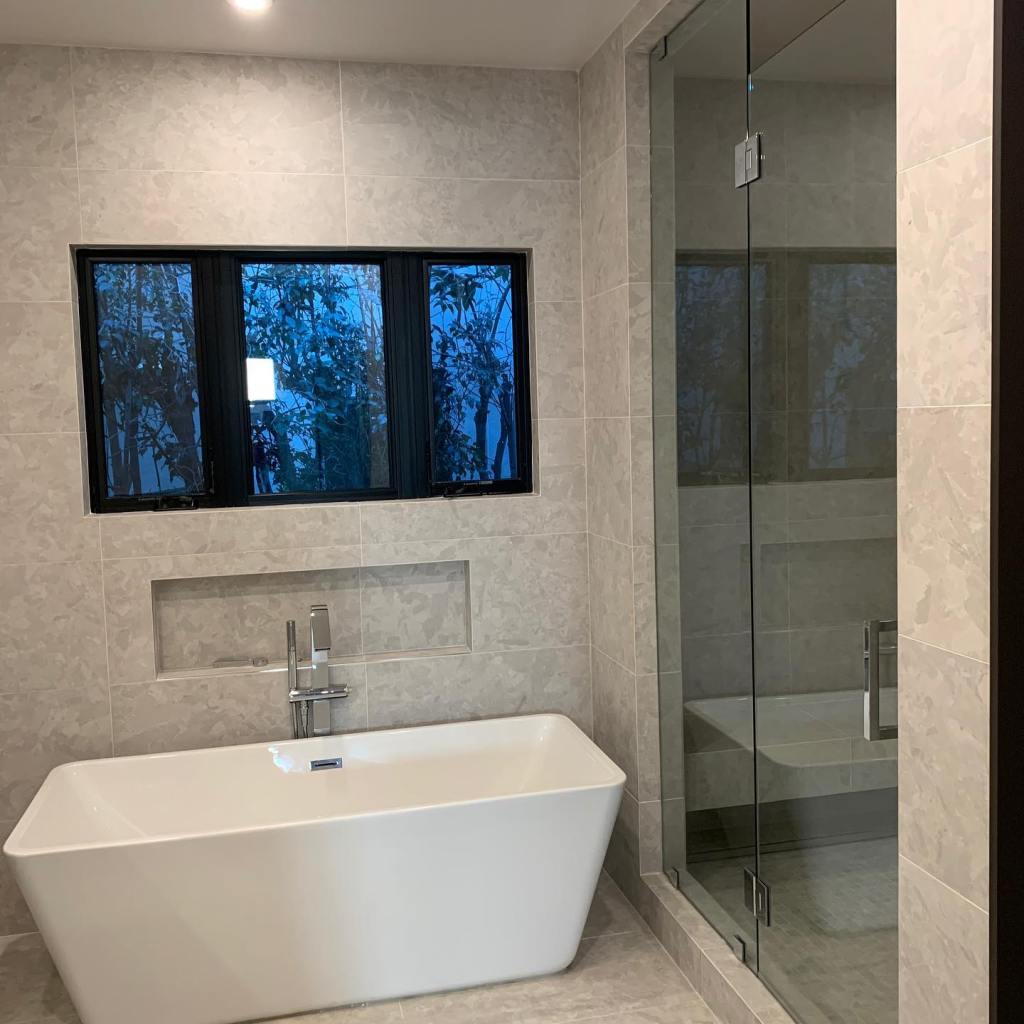 Double casement window with center fixed pane and frameless shower enclosure