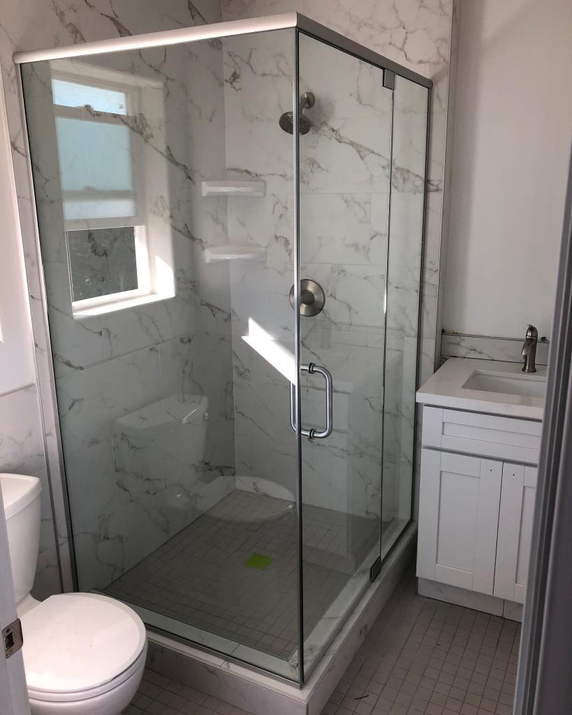 Narrow frame glass shower enclosure with brushed nickel hardware