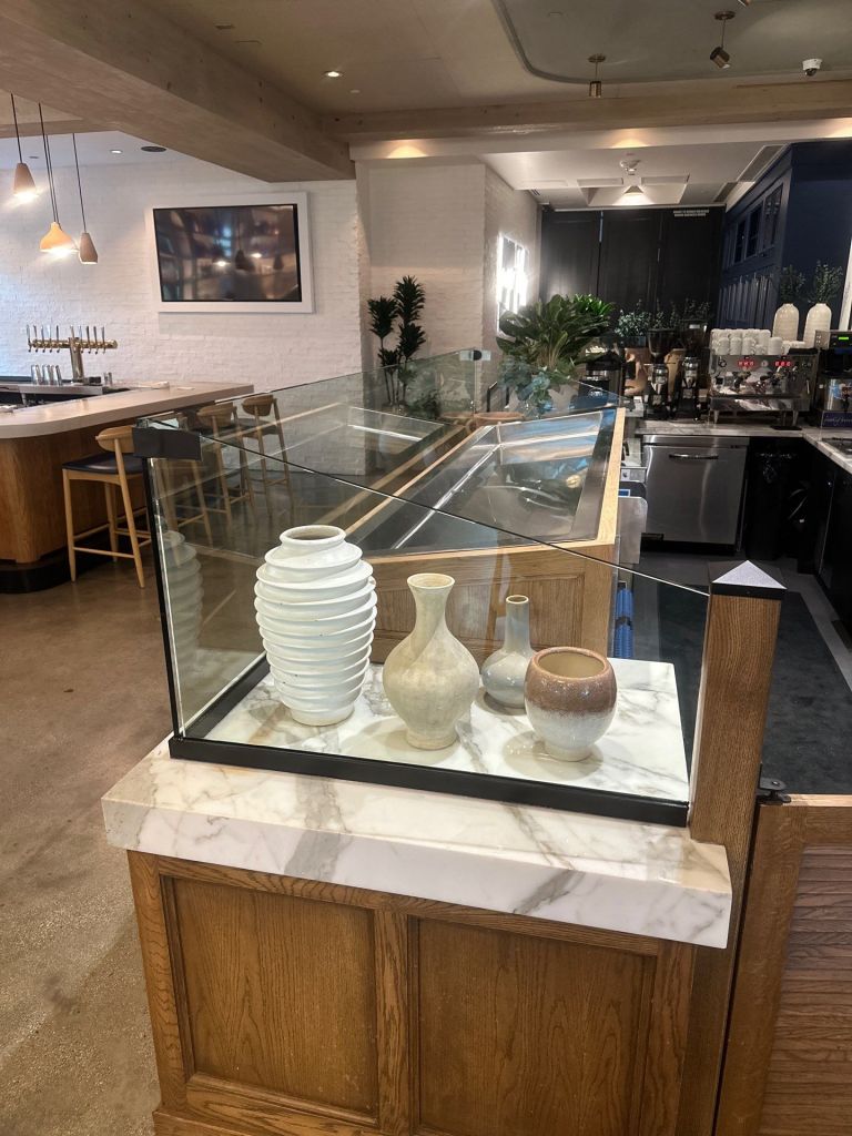 Glass enclosure for a restaurant counter displaying decorative vases