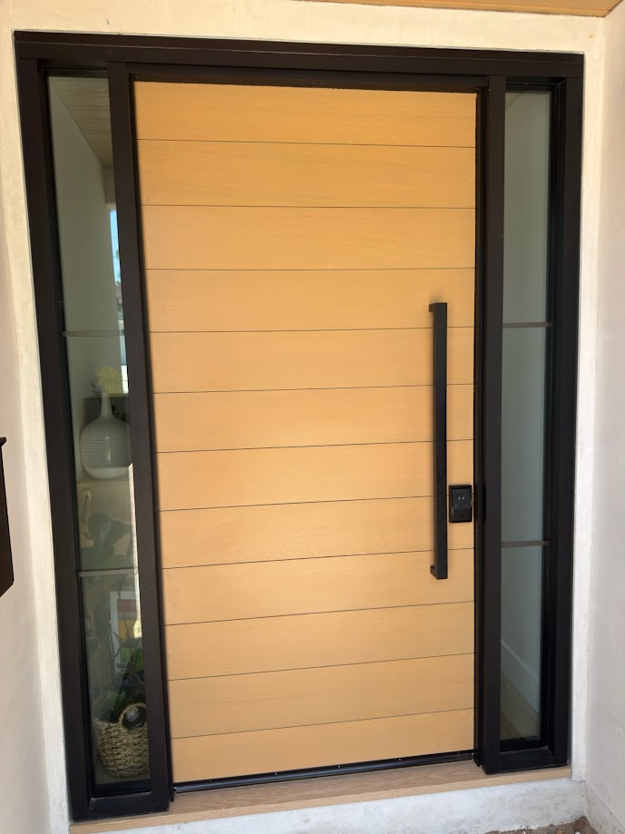 Wood slab door with horizontal panel pattern, bronze anodized aluminum frame, and two glass sidelites.